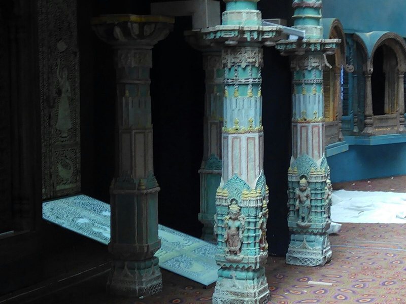 Carved painted pillars with a glowing floor panel at Mumbai Airport